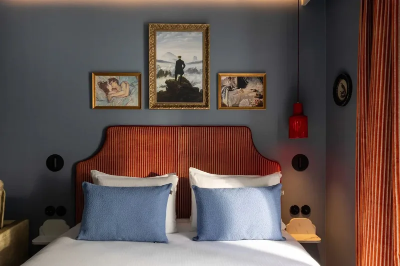 Photographie de la chambre bleue réalisée : tête de lit orange, coussins bleus et trois tableaux, Grand Hôtel de Turin