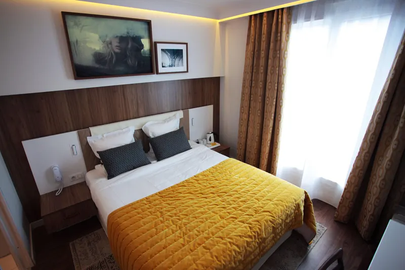 Hôtel Eiffel Turenne – Chambre, couvre-lit moutarde et photographies encadrées