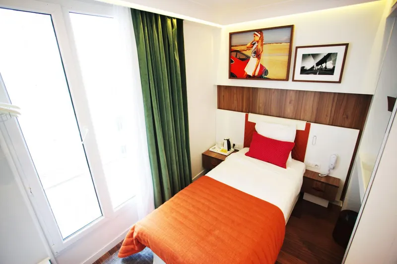Hôtel Eiffel Turenne – Chambre lumineuse, couvre-lit orange et rideaux verts