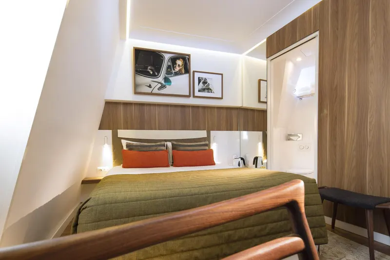 Hôtel Eiffel Turenne – Chambre, couvre-lit vert et banc en bois