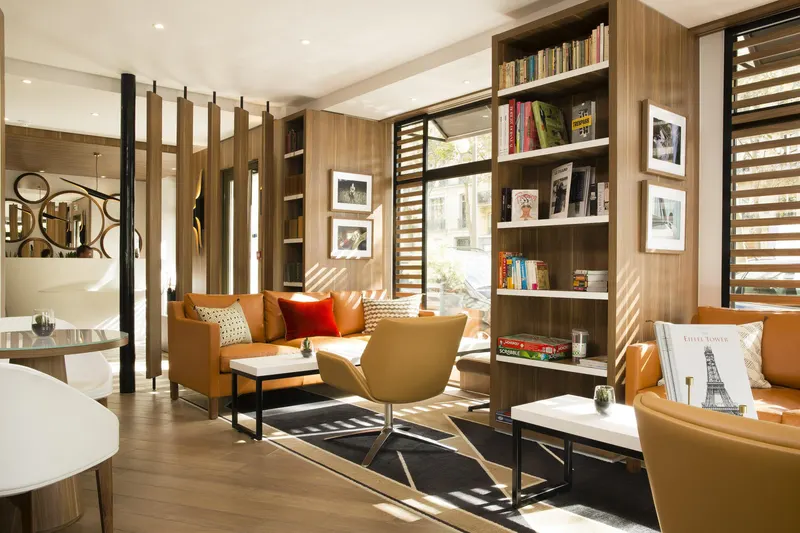 Hôtel Eiffel Turenne – Salon, fauteuils cognac et bibliothèque