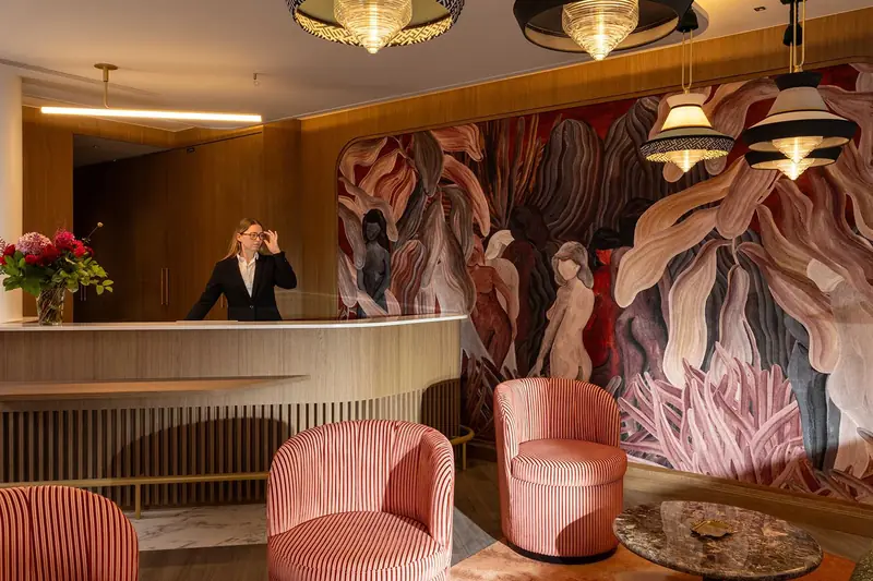 Lobby : réception en bois, fresque murale et fauteuils roses rayés – Grand Hôtel de Turin