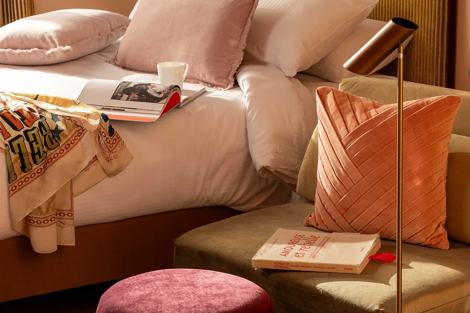 Chambre baignée de soleil : coussins roses, banquette en velours, lampe laiton et livre posé – Grand Hôtel de Turin
